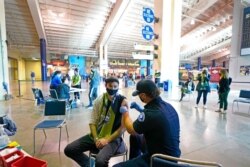 FILE - Austin Kennedy, left, a Seattle Sounders season ticket holder, gets the Johnson & Johnson COVID-19 vaccine at a clinic in a concourse at Lumen Field, May 2, 2021.