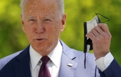 U.S. President Joe Biden pulls off his face mask as he arrives to speak about loosening coronavirus mask guidelines, outside the White House in Washington, April 27, 2021.