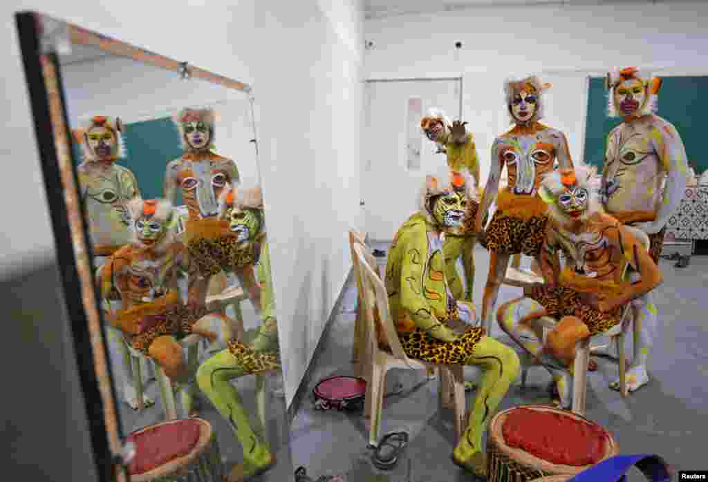 Artists painted to look like tigers are reflected in a mirror backstage as they wait to perform during a cultural event in Bengaluru, India.