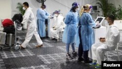 Travelers receive tests for the COVID-19 at a pre-departure testing facility, as countries react to the new coronavirus Omicron variant, outside the international terminal at Sydney Airport in Sydney, Australia, Nov. 29, 2021. 