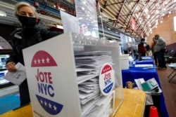 A voter drops off her absentee ballot during early voting at the Park Slope Armory YMCA, in the Brooklyn borough of New York, Oct. 27, 2020.