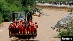 Rescue workers are transported into an earthquake zone on a front loader in Zhaotong, Yunnan province, August 5, 2014.