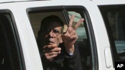Tersangka pembajak pesawat EgyptAir, Seif Eddin Mustafa mengacungkan jari tanda damai dari dalam mobil polisi saat meninggalkan pengadilan di Larnaca, Siprus (30/3). 