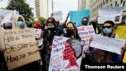 People carry signs to condemn the violence against women and girls during a protest in Karachi, July 30, 2021