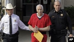 Former Penn State University assistant football coach Jerry Sandusky, center, is escorted by police as he leaves the Centre County Courthouse after being sentenced in Bellefonte, Pa., Tuesday, Oct. 9, 2012. 