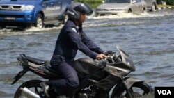 Seorang aparat di Thailand mengendarai sepeda motornya di tengah-tengah banjir yang masih merendam Bangkok, dekat Bandara Don Muang.