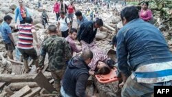 A handout picture released by the Colombian Army press office shows people helping to carry a woman after mudslides following heavy rains in Mocoa, April 1, 2017.