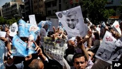 Supporters of presidential candidates Ali Akbar Velayati, shown in the poster at right, and Saeed Jalili, center on the poster, attend a street campaign after Friday prayers, Tehran, Iran, June 7, 2013. 