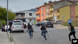 Turkish police officers run for cover during a gunfight near the site of an overnight explosion at a police station in Istanbul's Sultanbeyli neighborhood, Aug. 10, 2015. 