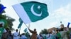 FILE - A man from the Pakistan's Hindu community waves a national flag during a rally expressing solidarity with the people of Kashmir, in Peshawar, Pakistan, Aug. 14, 2019.