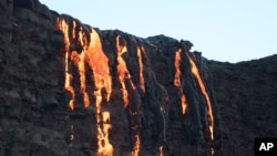 FILE - Lava from Kilauea, an active volcano on Hawaii's Big Island, flows into the ocean as seen from a boat off the coast of Volcanoes National Park near Kalapana, Hawaii, Aug. 9, 2016. 
