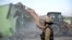 FILE - A police officer gestures as a bulldozer demolishes a property during a government demolition drive in Haldwani in the northern state of Uttarakhand, India, on Feb. 8, 2024.