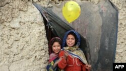 Internally displaced Afghan children play outside their temporary home at a refugee camp in Kabul, Afghanistan.