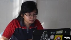 ឡុង គឹមហ៊ាង បុគ្គលិក​នៃអង្គការ​ក្រុម​ការងារ​ពិសេស​សិទ្ធិ​លំនៅ​ដ្ឋាន​​សំឡឹង​មើល​គម្រោង​​ការងារ​​របស់នាង​​លើ​កញ្ចក់​កំព្យួទ័រ​យូរដៃ​របស់នាង។​