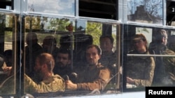 Sebuah bus yang membawa anggota militer Ukraina yang menyerah di pabrik baja Azovstal meninggalkan Mariupol dengan dikawal oleh militer pro Rusia, Sabtu, 20 Mei 2022. (Foto: Alexander Ermochenko/Reuters)