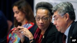 Margarette May Macaulay, center, president of the Inter-American Commission on Human Rights, confers with fellow commissioner Joel Hernandez Garcia, front, as commissioner Antonia Urrejoia, back, listens during a hearing Oct. 5, 2018, at the University of Colorado in Boulder, Colo. Human rights and advocacy groups from Latin America and U.S border states are pressing for access to an FBI DNA database to help identify the remains of hundreds of migrants reported missing along the U.S.-Mexico border.