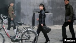 Warga melewati sepeda listrik yang sedang diparkir di Pyongyang, Korea Utara (6/5).