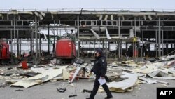 Ukrajinski policajac prolazi pored oštećenog skladišta pošte nakon raketnih udara u selu Korotych, u oblasti Harkov.