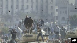 Supporters of President Hosni Mubarak, foreground , fight with anti-Mubarak protesters, rear, standing on army tanks in Cairo, February 2, 2011