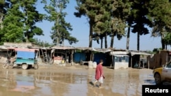 Seorang anak laki-laki berjalan melewati jalan yang terendam banjir di Sheikh Jalal, Provinsi Baghlan, Afghanistan, 12 Mei 2024. (Foto: Sayed Hassib/Reuters/Arsip)