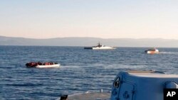 Ilustrasi - Sebuah perahu sarat penumpang migran (kiri), dan kapal-kapal Turki di belakangnya, di selat antara pulau Lesbos di Yunani timur dan pantai Turki, 2 April 2021. (Penjaga Pantai Hellenic melalui AP)