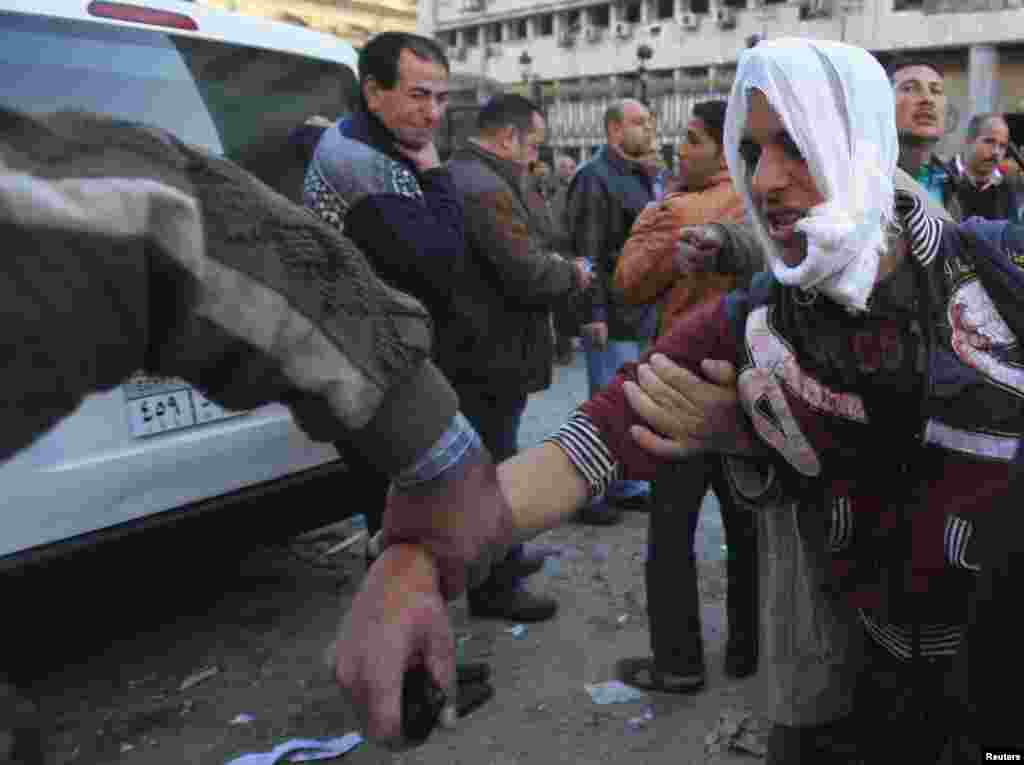 An injured police officer is assisted by people out of the damaged Cairo Security Directorate after a bomb attack in downtown Cairo, Jan. 24, 2014. 