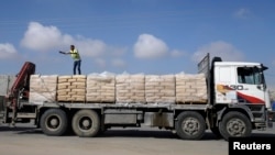 FILE - A Palestinian worker stands atop a truck loaded with bags of cement after entering Gaza, at the Kerem Shalom crossing in Rafah in the southern Gaza Strip, Nov. 10, 2014.