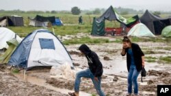 Un couple se déplace à travers une partie inondée du camp de migrants en Idomeni, Grèce, 21 mai 2016. 