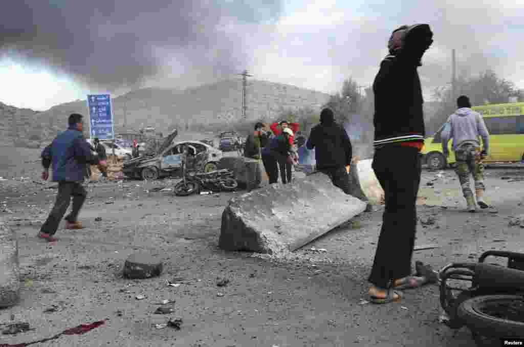Men react as others rush at the site of a car bomb attack at the Bab al-Hawa border crossing between Syria and Turkey, in Idlib, Jan. 20, 2014.