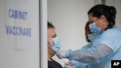 FILE - Medical staff administer the third dose booster Pfizer vaccine shot to a man at the Matei Bals hospital in Bucharest, Romania, Sept. 28, 2021. 