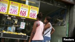 Women look at prices at a food market in Rio de Janeiro, Brazil, Jan. 21, 2016.