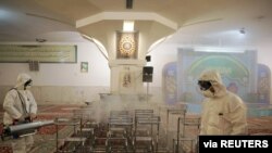 FILE - Members of a medical team spray disinfectant to sanitize indoor place of Imam Reza's holy shrine, following the coronavirus outbreak, in Mashhad, Iran, Feb. 27, 2020.