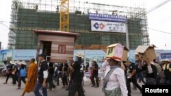 ពលរដ្ឋ​អ្នក​ក្រុង​ភ្នំពេញ​ដែល​ជា​អតីត​អ្នក​រស់​នៅ​សហគមន៍​បឹងកក់ បុរីកីឡា និង​សហគមន៍​ផ្សេងៗ​ទៀត ​មាន​កាន់​រូបសំណាក​ផ្ទះ​សម្បែង​ដើរ​ក្បួន​​​ពី​មុខ​សំណង់​ថ្មី​មួយ នៅ​ក្នុង​ឱកាស​ទិវា​សិទ្ធិ​​លំនៅដ្ឋាន​អន្តរជាតិ​​នៅ​កណ្តាល​រាជធានី​ភ្នំពេញ​កាល​ពី​ថ្ងៃ​ទី​​៥ ខែ​តុលា ឆ្នាំ​២០១៥។