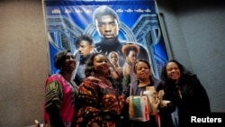 A group of women pose for a photo in front of a poster advertising the film "Black Panther" on its opening night of screenings at the AMC Magic Johnson Harlem 9 cinemas in Manhattan, New York, U.S., February 15, 2018. (REUTERS/Andrew Kelly)