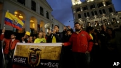 FILE - Protesters demand the government remove Julian Assange's Ecuadorian nationality, carrying a sign that reads in Spanish "Nationality is earned, not given away," outside the government palace in Quito, Ecuador, Oct. 31, 2018.