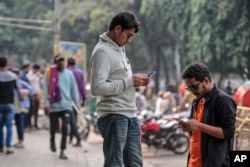 FILE - People engage with their mobile phones at Dhaka University area, Bangladesh, Dec.21, 2023. Artificial intelligence is supercharging the threat of election disinformation worldwide. (AP Photo/Mahmud Hossain Opu, File)