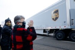 Nancy Galloway, left, and Susan Deur cheer as trucks carrying the first shipment of the COVID-19 vaccine that is being escorted by the U.S. Marshals Service, leave Pfizer's Global Supply facility in Kalamazoo, Michigan, Dec. 13, 2020.