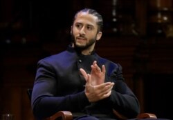 FILE - NFL football quarterback Colin Kaepernick applauds during W.E.B. Du Bois Medal ceremonies at Harvard University in Cambridge, Mass.