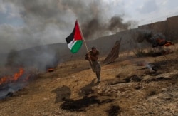 FILE - Palestinian Ashraf Abu Rahma runs away from tear gas fired by Israeli troops, not pictured, during a demonstration in the West Bank town of Bilin, near Ramallah, Sept. 9, 2011.