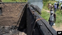 Un homme ramassant des corps à enterrer dans une fosse commune s'approche d'une hutte brûlée contenant des cadavres calcinés, à la périphérie de Yei, dans le sud du Soudan du Sud, le 15 novembre 2016.