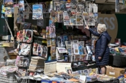 A woman reads newspapers headlines of the killing of a Greek journalist in Athens, April 10, 2021.