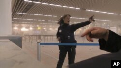 Sur cette photo prise par Ralph Usbeck, une policière demande aux passagers d'utiliser le terminal a l'abri des explosions mardi le 22 mars 2016.
