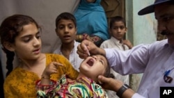 Petugas kesehatan Pakistan memberikan vaksin polio kepada seorang anak di Rawalpindi, Pakistan, Mei 2014.