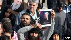 Seorang pria memegang foto Mayjen Qasem Soleimani yang tewas akibat serangan AS, dalam aksi protes di Teheran, 3 Januari 2020. 