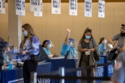 People are processed at the entrance to an empty department store being used as a vaccination center during the outbreak of the coronavirus disease (COVID-19) in Chula Vista, California, Jan. 21, 2021.