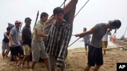 Penduduk desa di provinsi Thanh Hoa, Vietnam, bergotong royong memindahkan kapal nelayan ke pantai, 14 September 2017. Vietnam dihantam topan Doksuri, Kamis (14/9), topan tropis terkuat yang melanda negara Asia Tenggara dalam beberapa tahun ini. (Trinh Duy Hung / Kantor Berita Vietnam via AP)
