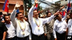 Cambodia's opposition leader Sam Rainsy, center, of the Cambodia National Rescue Party waves along with his party Vice President Kem Sokha, third from left, during a march in Phnom Penh, file photo. 