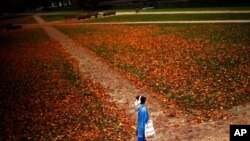 A woman, masked to prevent the spread of COVID-19, walks along Cinquantenaire park in Brussels, Oct. 23, 2020. Belgian Prime Minister Alexander De Croo stopped short Friday of imposing another full lockdown but introduced new restrictive measures.