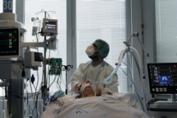 FILE - Health staff attends to a patient at the coronavirus disease (COVID-19) dedicated ICU unit of the Tras-Os-Montes E Alto Douro Hospital, amid the COVID-19 pandemic in Vila Real, Portugal, Feb. 22, 2021.