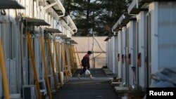 Seorang warga masuk ke dalam kompleks perumahan sementara tempat tinggal warga yang dievakuasi dari Tamura di Funahiki, Fukushima (1/4).